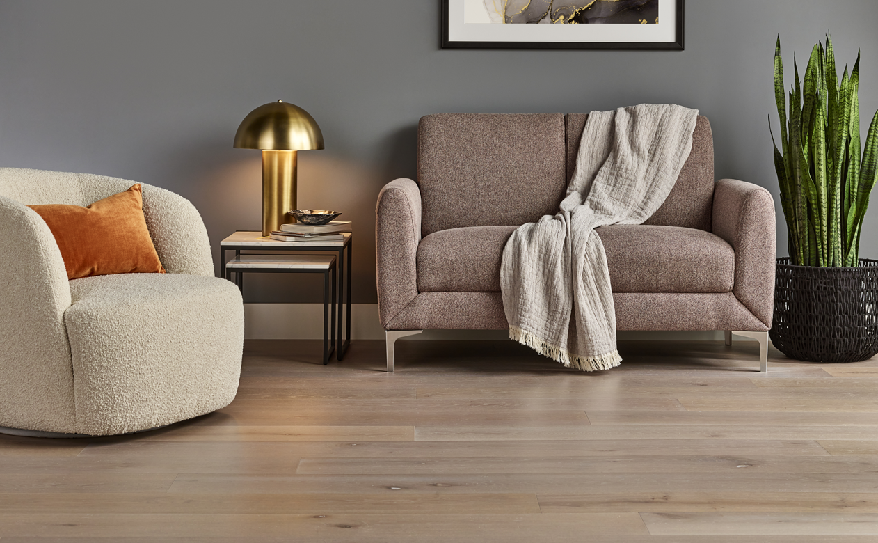 Light hardwood floor with grey living room, orange pillow 